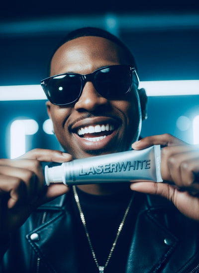 Smiling man holding LaserWhite toothpaste